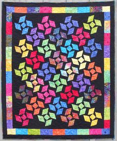 a multicolored quilt with many different shapes and sizes on the front, along with black background