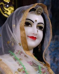 a close up of a person wearing a white mask with gold and green decorations on it