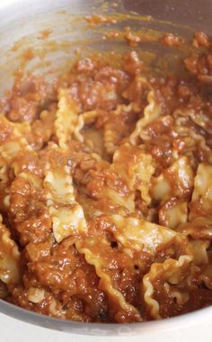 pasta and meat sauce are mixed together in a pot on top of the stovetop