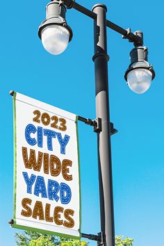 a sign that says city wide yard sales hanging from a street light pole in front of a blue sky