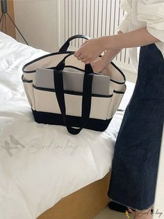 a woman holding a black and white bag on top of a bed