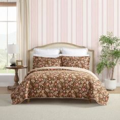 a bed sitting in a bedroom next to a window covered in pink and brown flowers