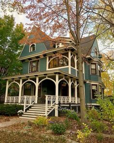 a large green house with white trim on the front porch and steps leading up to it