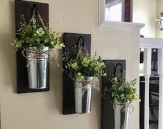 three metal buckets with plants in them hanging on a wall next to a mirror