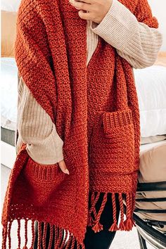 a woman wearing an orange knitted shawl and holding a cell phone in her hand