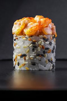 a sushi dish with rice, nuts and other toppings on the top is sitting on a black surface