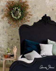 a bedroom with a black headboard and green pillows