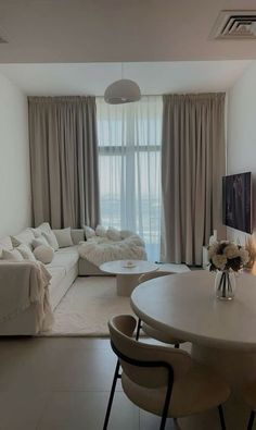 a living room filled with furniture and a white table in front of a large window