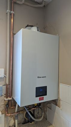 a white tank sitting in the middle of a room next to pipes and piping