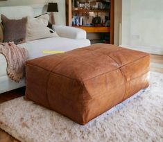 a large brown ottoman sitting on top of a rug in front of a white couch