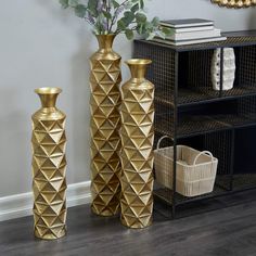 three gold vases sitting on top of a wooden floor