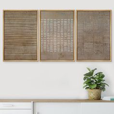 three framed art pieces hang on the wall above a white dresser with a potted plant