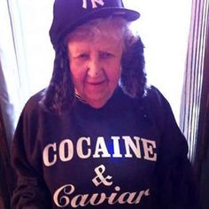 an older woman wearing a new york yankees sweatshirt and cap while standing in front of a mirror