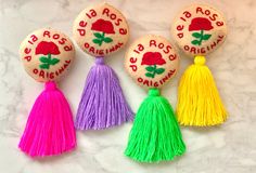 four decorated rocks with tassels on them sitting on a marble counter top next to each other