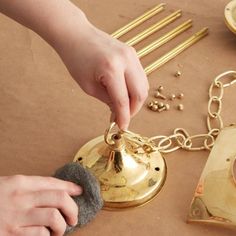 a person is holding a bell on a table with other items and gold chains around it