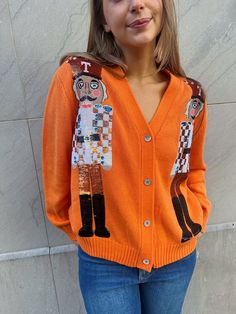 Look festive and stay cozy this holiday season with the Queen of Sparkles Orange Vols Nutcracker Cardigan! Show off your gameday team pride while also rocking a festive, sequined nutcracker design. This true-to-size Orange Vols Nutcracker Cardigan is a unique combination of style and comfort. Featuring a striking sequined nutcracker design, it allows you to show off your team loyalty and holiday spirit at the same time. Runs true to size Nutcracker Design, Queen Of Sparkles, Sparkle Sweater, Sequin Sleeve, Sequin Sweater, Sequin Mini Skirts, Vintage Havana, Sequin Mini, Loose Sweater