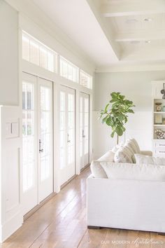 a living room with white furniture and lots of windows