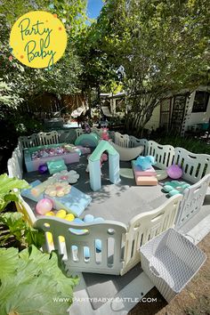 an inflatable baby play yard with toys and decorations on the ground, surrounded by greenery