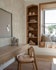 a wooden chair sitting in front of a window next to a desk with a mirror on it