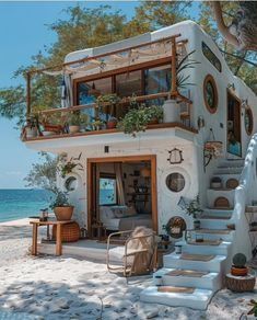 a house on the beach with stairs leading up to it and potted plants outside