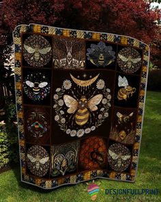 a patchwork quilt with bees and flowers on it in front of some trees,