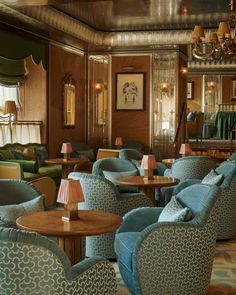 the interior of a restaurant with blue and green chairs, tables, and chandeliers