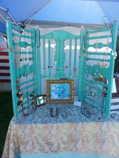 a table with an open screen on it and jewelry hanging from the sides, in front of a tent