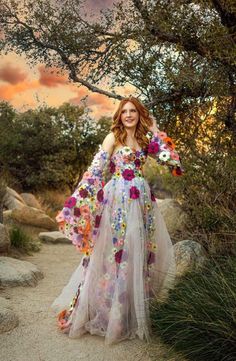 a woman in a dress standing on a dirt path