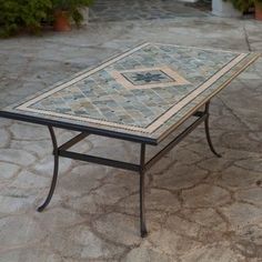 a table that is sitting on some kind of stone flooring in front of potted plants