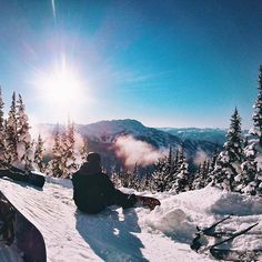 two people sitting in the snow on top of a mountain