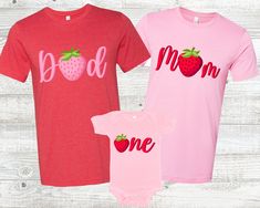 three baby onesuits with the words mom and one strawberry on them, sitting next to each other