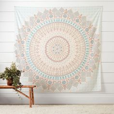 a large tapestry hanging on the wall next to a wooden bench and potted plant