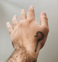 a man's hand with a tattoo on the middle of his left arm, and a long curved black line drawn across it