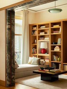 a living room filled with lots of furniture and bookshelves next to a window