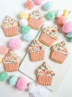 decorated cookies and pom - poms on a white surface with pastel colors