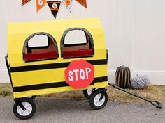 a child's yellow and black school bus with stop sign painted on it sitting in front of a white wall