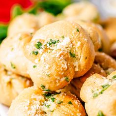 several rolls covered in parmesan cheese and sprinkled with herbs on a plate