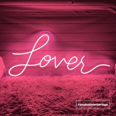 a pink neon sign that says love in the middle of a room with fur on the floor