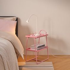 a pink table lamp next to a bed with pillows and blankets on the floor in a bedroom