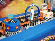 a table topped with cakes and toys on top of a blue table cloth covered table