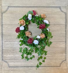 a wreath made out of flowers and ivy on a wooden background with the letter o