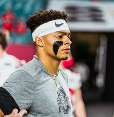 a young man with black face paint on his face and headband in front of other players