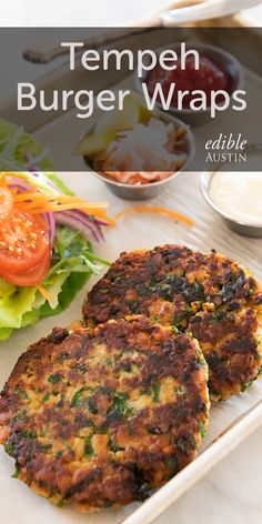 two crab cakes on a plate with lettuce and tomato in the background, topped with dressing