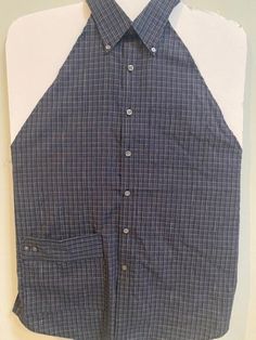 a blue and white checkered shirt is hanging on a wall with a pair of scissors