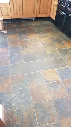 a kitchen with black appliances and wood cabinets on the counter top, tile flooring