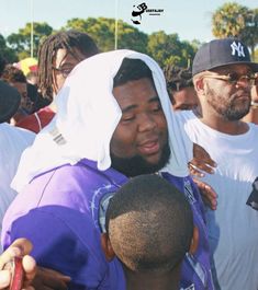 two men hugging each other in front of a group of people wearing white hoodies