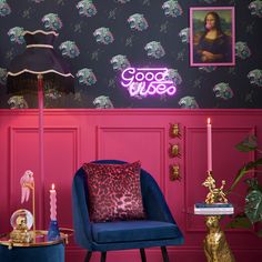 a room with pink walls, blue chairs and a neon sign that reads good vibes