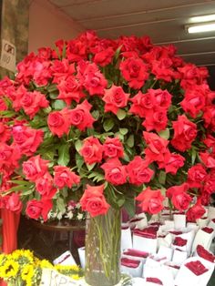 a vase filled with red roses sitting on top of a table next to other flowers