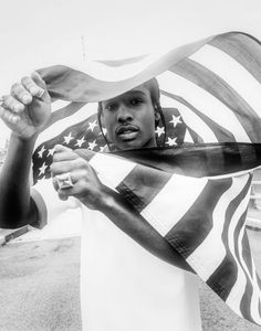 a black and white photo of a woman holding an american flag scarf over her head