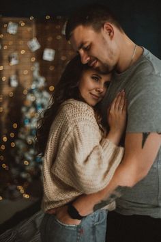 a man and woman hugging in front of a christmas tree